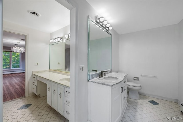 bathroom with two vanities, toilet, tile patterned floors, and baseboard heating