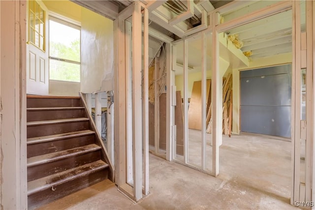misc room with stairs and unfinished concrete flooring