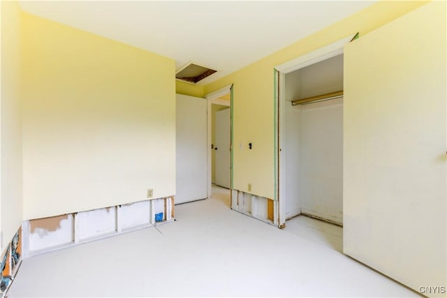 unfurnished bedroom with attic access and a closet