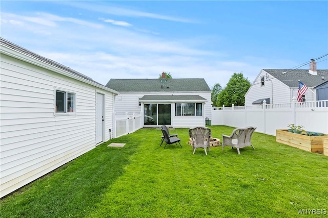 view of yard with a garden, a sunroom, and a fire pit