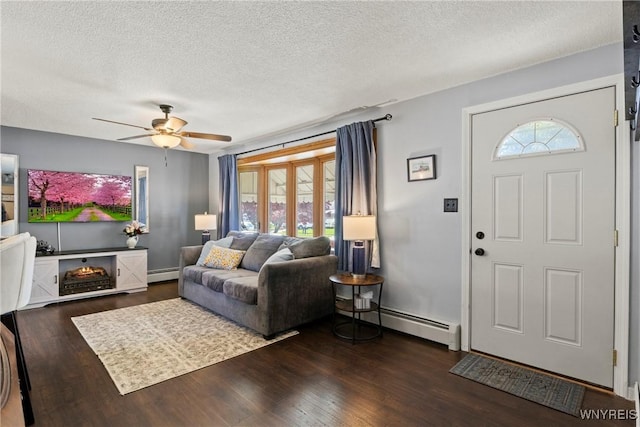 living room featuring a baseboard heating unit, a textured ceiling, ceiling fan, and dark wood-type flooring