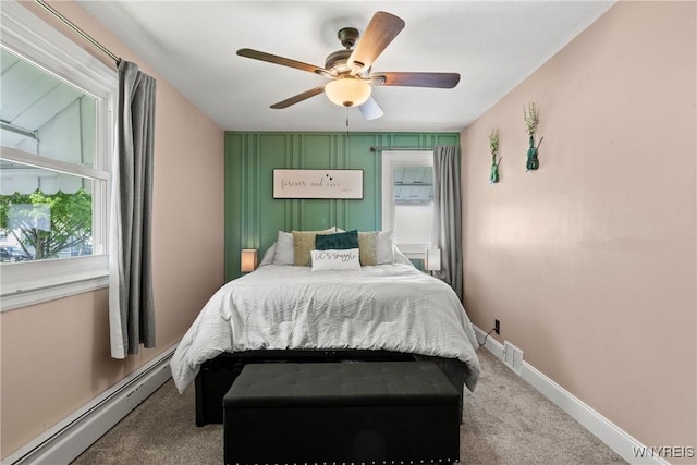 carpeted bedroom featuring a baseboard heating unit, multiple windows, ceiling fan, and baseboards