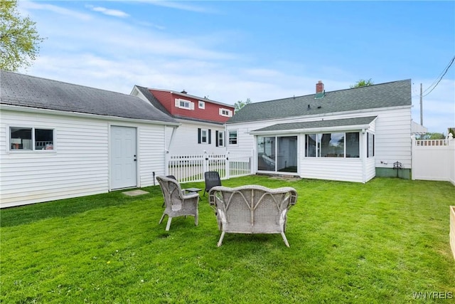 back of house with a sunroom, an outdoor fire pit, and roof with shingles