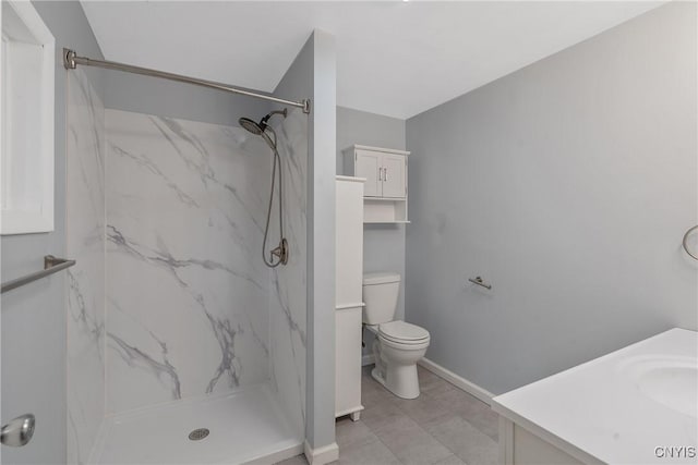 full bath with a marble finish shower, toilet, baseboards, and vanity