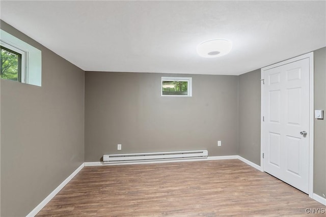 basement with a baseboard radiator, wood finished floors, healthy amount of natural light, and baseboards