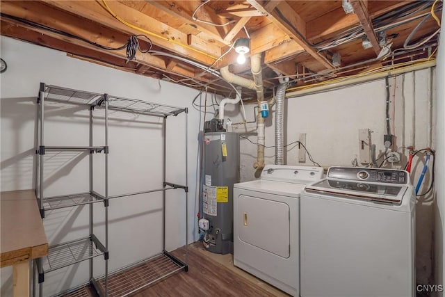 clothes washing area with water heater, washing machine and clothes dryer, and wood finished floors