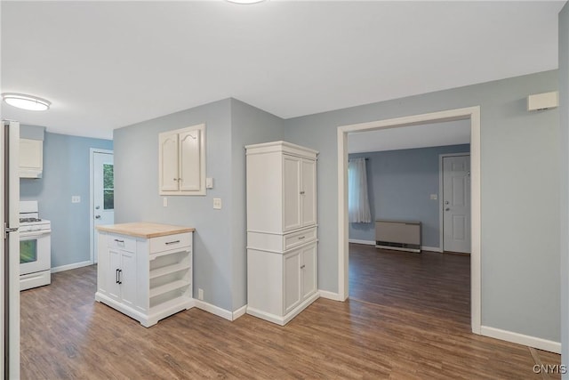 kitchen featuring white range with gas stovetop, wood finished floors, white cabinetry, baseboards, and butcher block counters