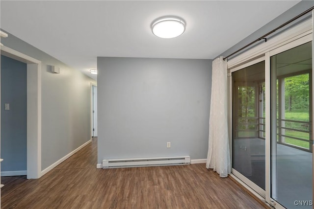 empty room with a baseboard heating unit, wood finished floors, and baseboards