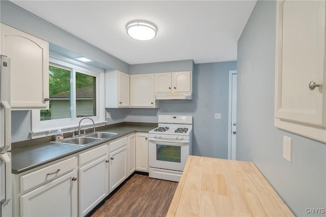 kitchen with white gas range oven, under cabinet range hood, a sink, dark wood-type flooring, and white cabinets