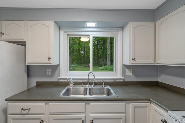 kitchen featuring a sink, dark countertops, and white cabinets