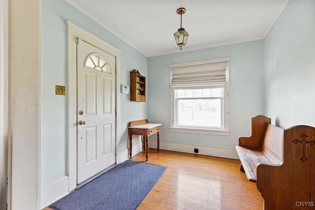 foyer entrance with wood finished floors, crown molding, and baseboards