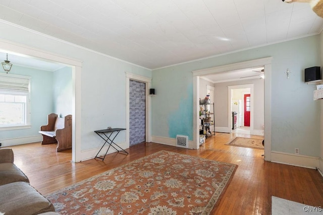 living area with wood-type flooring, crown molding, and baseboards
