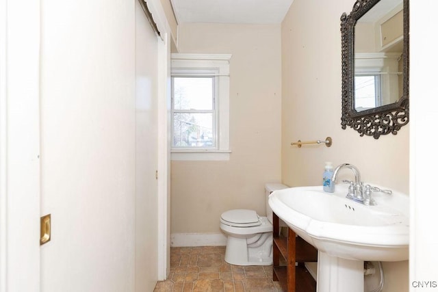 bathroom featuring toilet, baseboards, and a sink