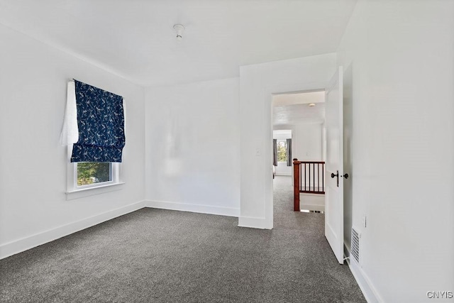 empty room featuring dark carpet and baseboards