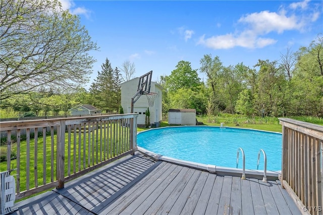 swimming pool featuring a deck, a storage shed, an outdoor structure, a lawn, and view of scattered trees