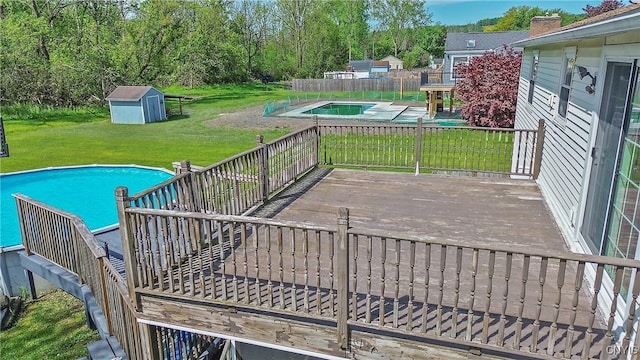 view of pool with a deck, a shed, and an outdoor structure