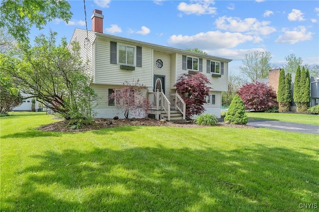 raised ranch featuring a chimney and a front yard