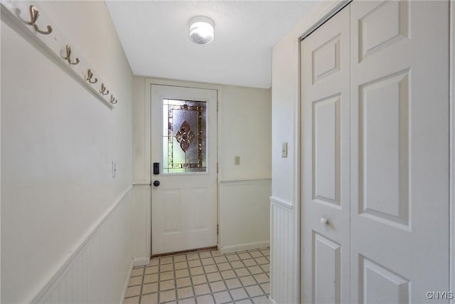 doorway to outside featuring a wainscoted wall and light tile patterned floors