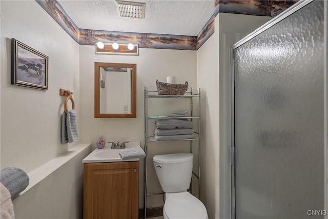 full bath featuring a shower stall, a textured ceiling, vanity, and toilet