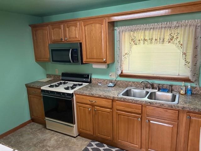214 Main St, Erwin, NY 14827 - kitchen with gas stove, stainless steel microwave, a sink, brown cabinets, and baseboards
