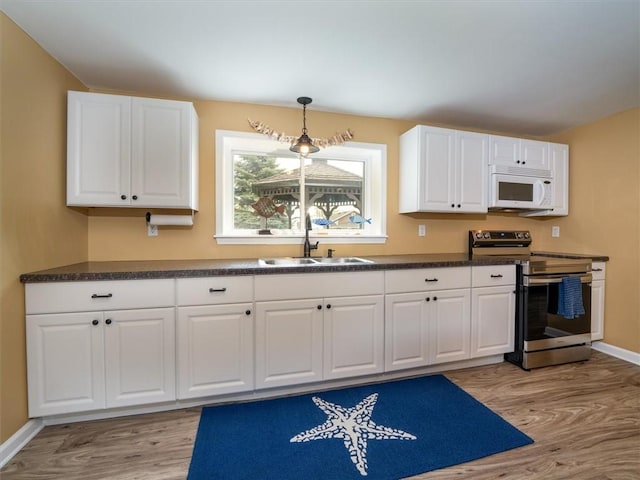 8521 W Buckingham St, Richmond, NY 14471 - kitchen with stainless steel electric stove, white microwave, a sink, dark countertops, and light wood-style flooring