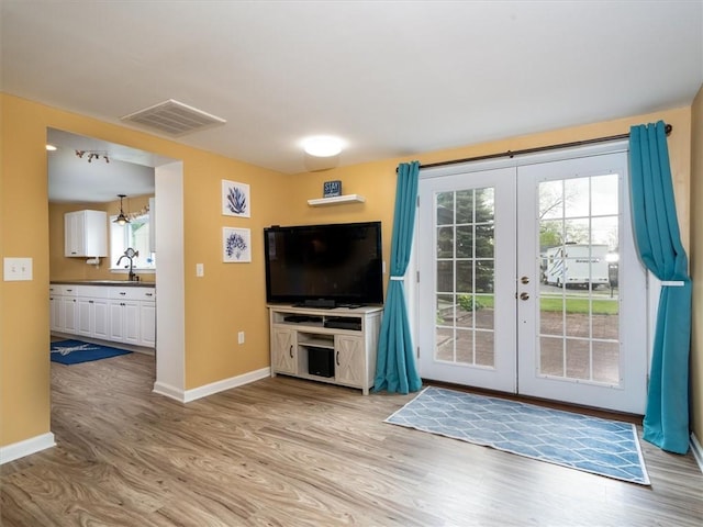 8521 W Buckingham St, Richmond, NY 14471 - unfurnished living room with light wood-type flooring, baseboards, french doors, and a sink