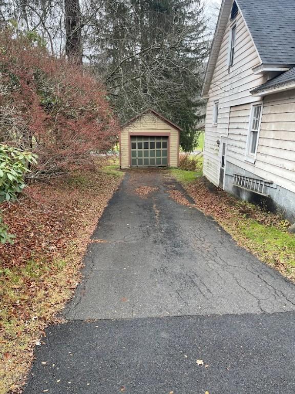 211 Main St, Delhi, NY 13753 - view of property exterior featuring asphalt driveway, a garage, an outdoor structure, and roof with shingles