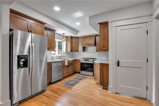kitchen featuring stainless steel appliances, a sink, light wood finished floors, light countertops, and recessed lighting