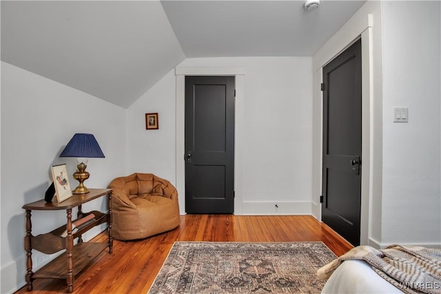 sitting room featuring wood finished floors, vaulted ceiling, and baseboards