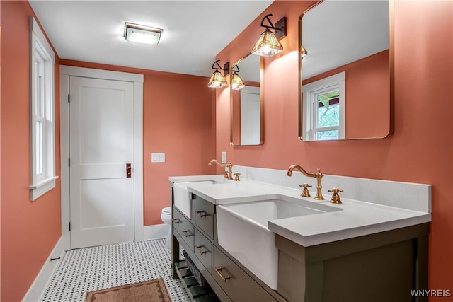 bathroom featuring baseboards, toilet, tile patterned floors, and double vanity