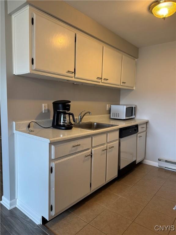 kitchen featuring stainless steel microwave, dishwasher, a sink, white cabinetry, and light countertops