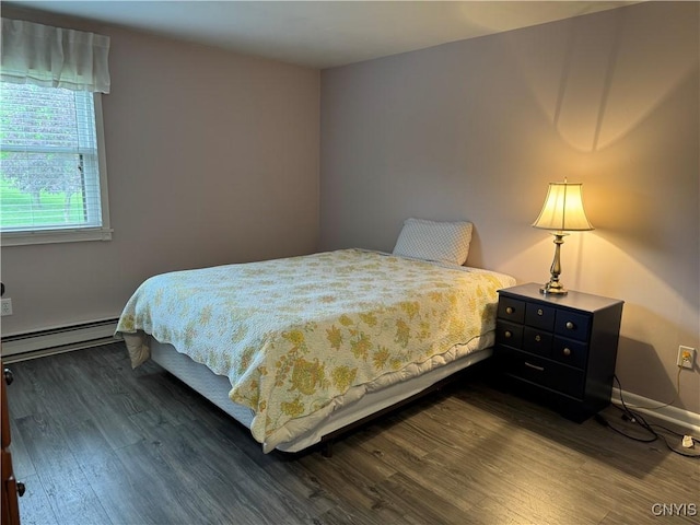 bedroom featuring a baseboard heating unit, dark wood-style floors, and baseboards