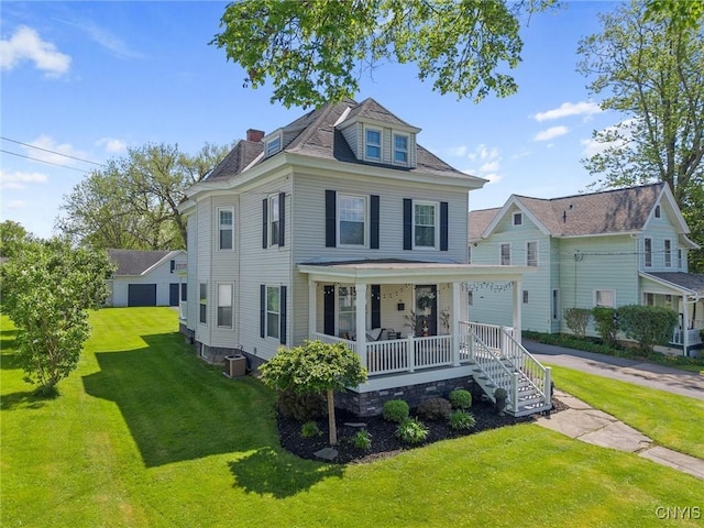 american foursquare style home featuring covered porch, a front yard, and central AC