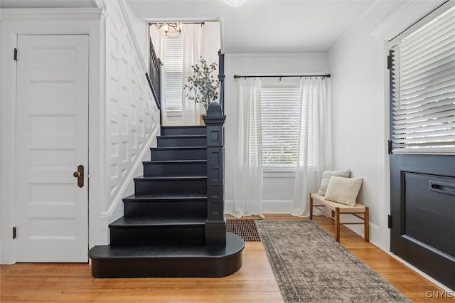 stairs with wood finished floors, crown molding, and baseboards