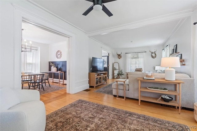 living area with wood finished floors, crown molding, a chandelier, and ceiling fan