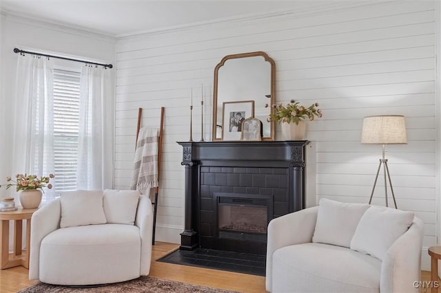 living area with wood finished floors, ornamental molding, and a fireplace with flush hearth