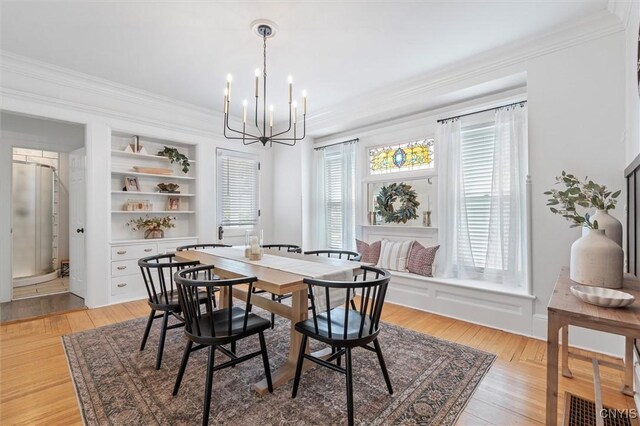 dining space featuring a chandelier, ornamental molding, and light wood-style floors