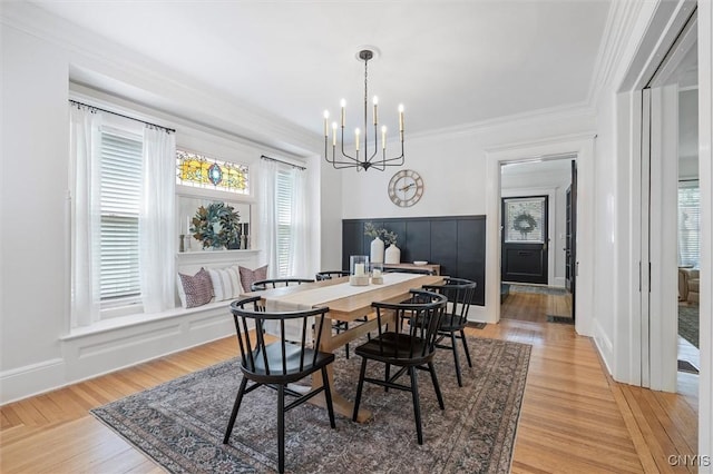 dining area with a chandelier, ornamental molding, and light wood-type flooring