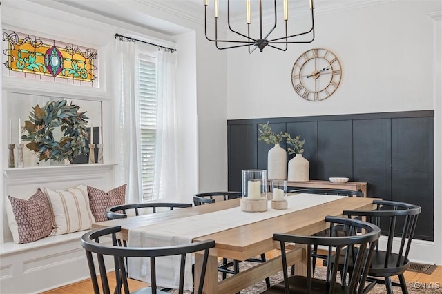 dining space featuring a chandelier, a decorative wall, and light wood-type flooring