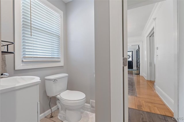 bathroom with baseboards, toilet, and plenty of natural light