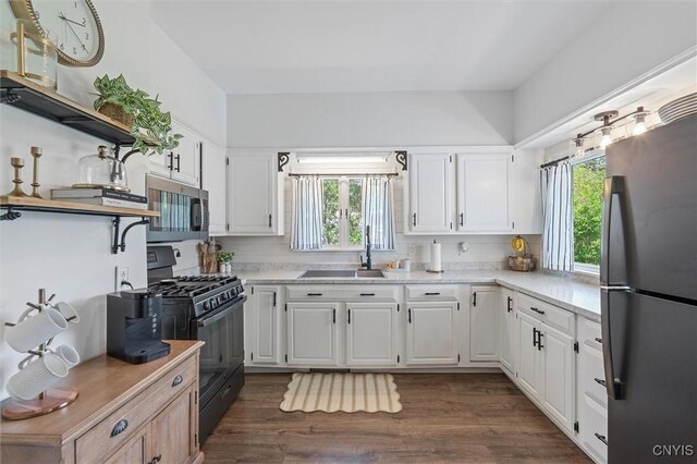 kitchen featuring stainless steel appliances, a sink, open shelves, and white cabinets