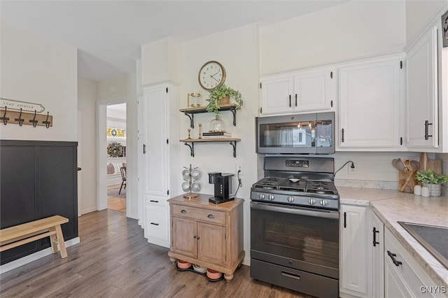 kitchen with stainless steel microwave, gas range, light countertops, white cabinets, and wood finished floors
