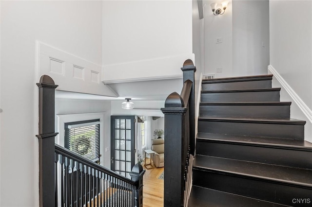 staircase with wood finished floors and a high ceiling