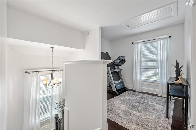 exercise area with wood finished floors, baseboards, and a chandelier