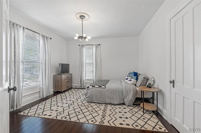 bedroom with multiple windows, hardwood / wood-style floors, a chandelier, and baseboards