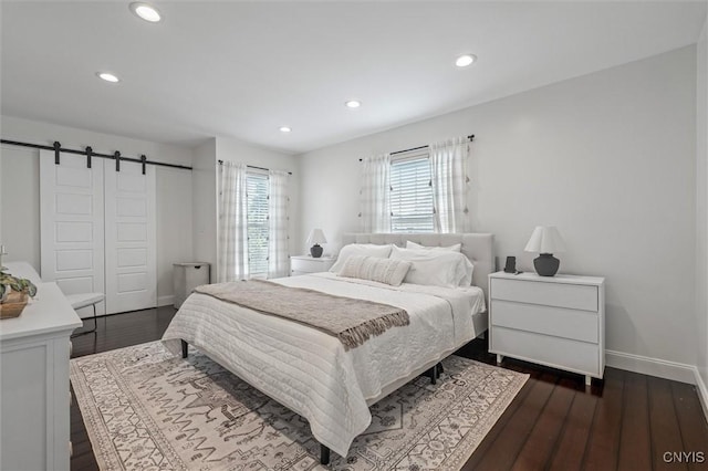 bedroom with recessed lighting, baseboards, a barn door, and dark wood finished floors
