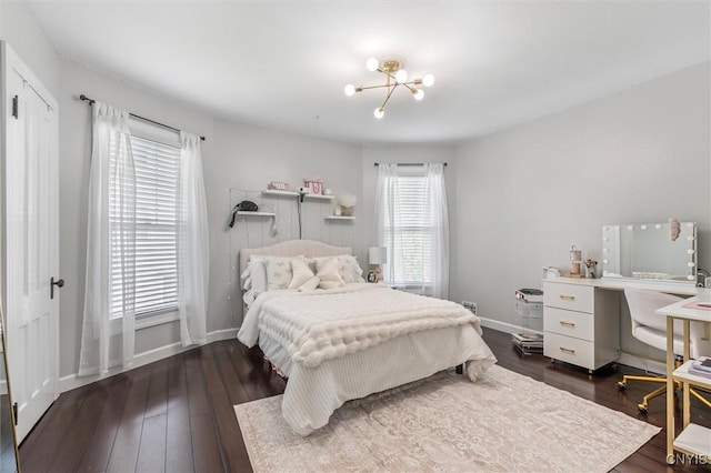 bedroom with a chandelier, dark wood-style flooring, and baseboards
