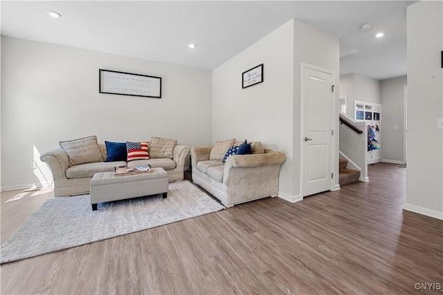 living area featuring wood finished floors, stairway, baseboards, and recessed lighting