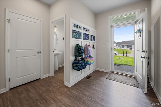 mudroom with dark wood finished floors and baseboards