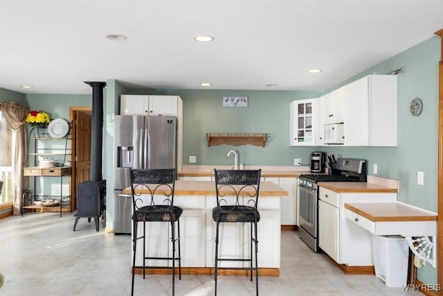 9910 Shorecliff Rd, Evans, NY 14006 - kitchen with stainless steel appliances, a wood stove, a center island, white cabinets, and recessed lighting